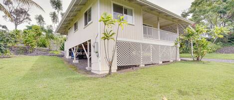 A single-story house with a porch, surrounded by a well-maintained lawn and tropical vegetation.