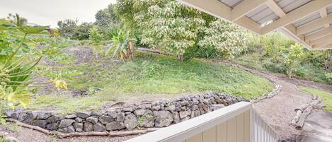 Un espacio al aire libre cubierto con un muro de piedra, una pendiente cubierta de césped y una variedad de plantas.