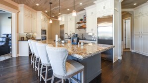 A spacious kitchen with a large island, white cabinetry, and a wooden ceiling. - Spacious Owasso Vacation Rental w/ Private Pool! (Owasso)
