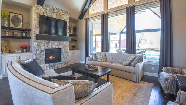 A cozy living room with a stone fireplace, a large window with curtains, and a comfortable seating area. - Spacious Owasso Vacation Rental w/ Private Pool! (Owasso)
