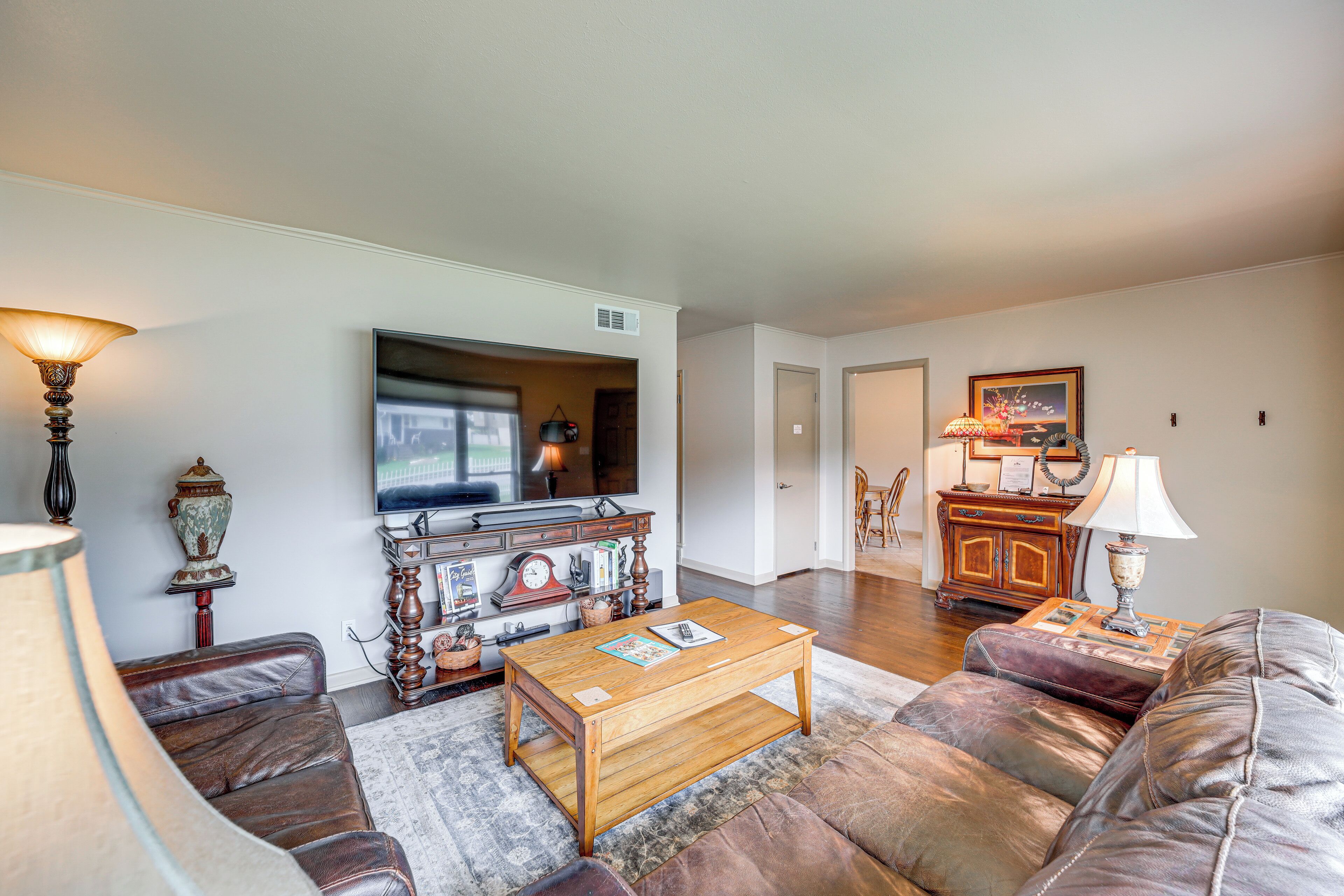 A living room with a wooden coffee table, leather sofa, and a television.