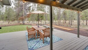 A covered outdoor patio with a wooden table and chairs, surrounded by a patterned rug. - Sunriver Resort Home: Near Skiing, Town & Trails (Bend)