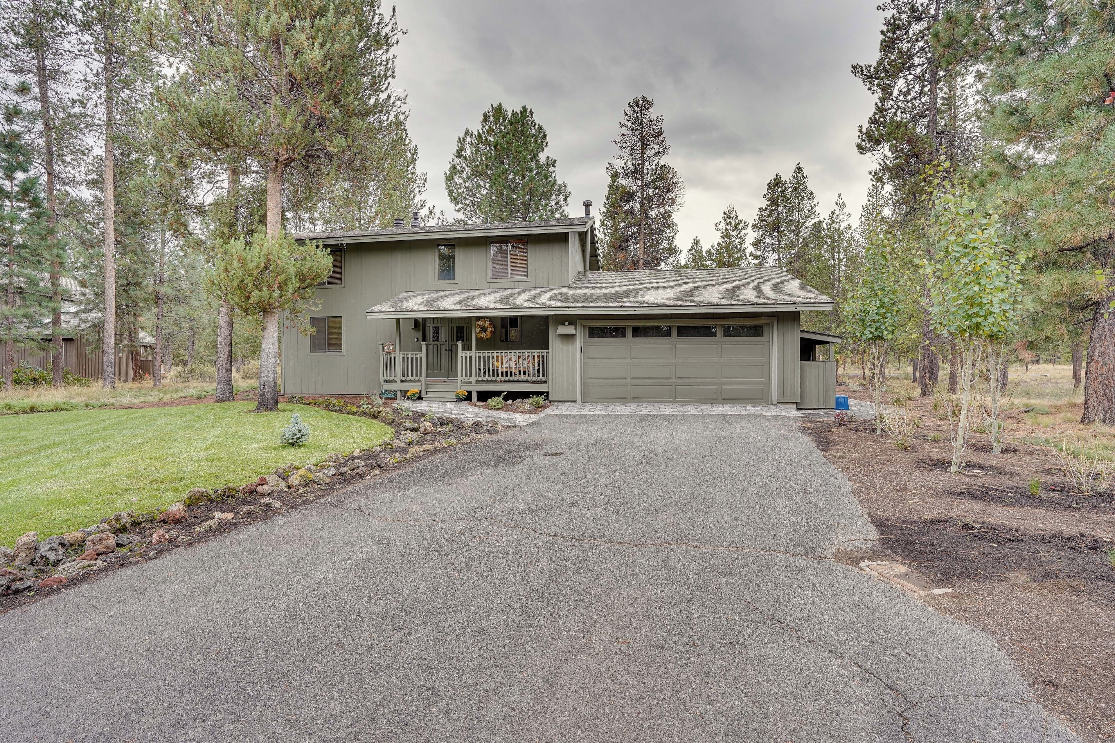 A two-story house with a garage, surrounded by trees and a well-maintained lawn.