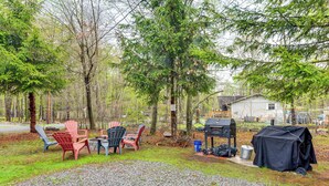 A backyard with Adirondack chairs, a grill, and a covered barbecue area. - Resort Amenities & Game Room: Arrowhead Lake Home! (Pocono Lake)