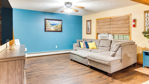 A living room with a sectional sofa, a ceiling fan, and a painting on the wall. - Resort Amenities & Game Room: Arrowhead Lake Home! (Pocono Lake)