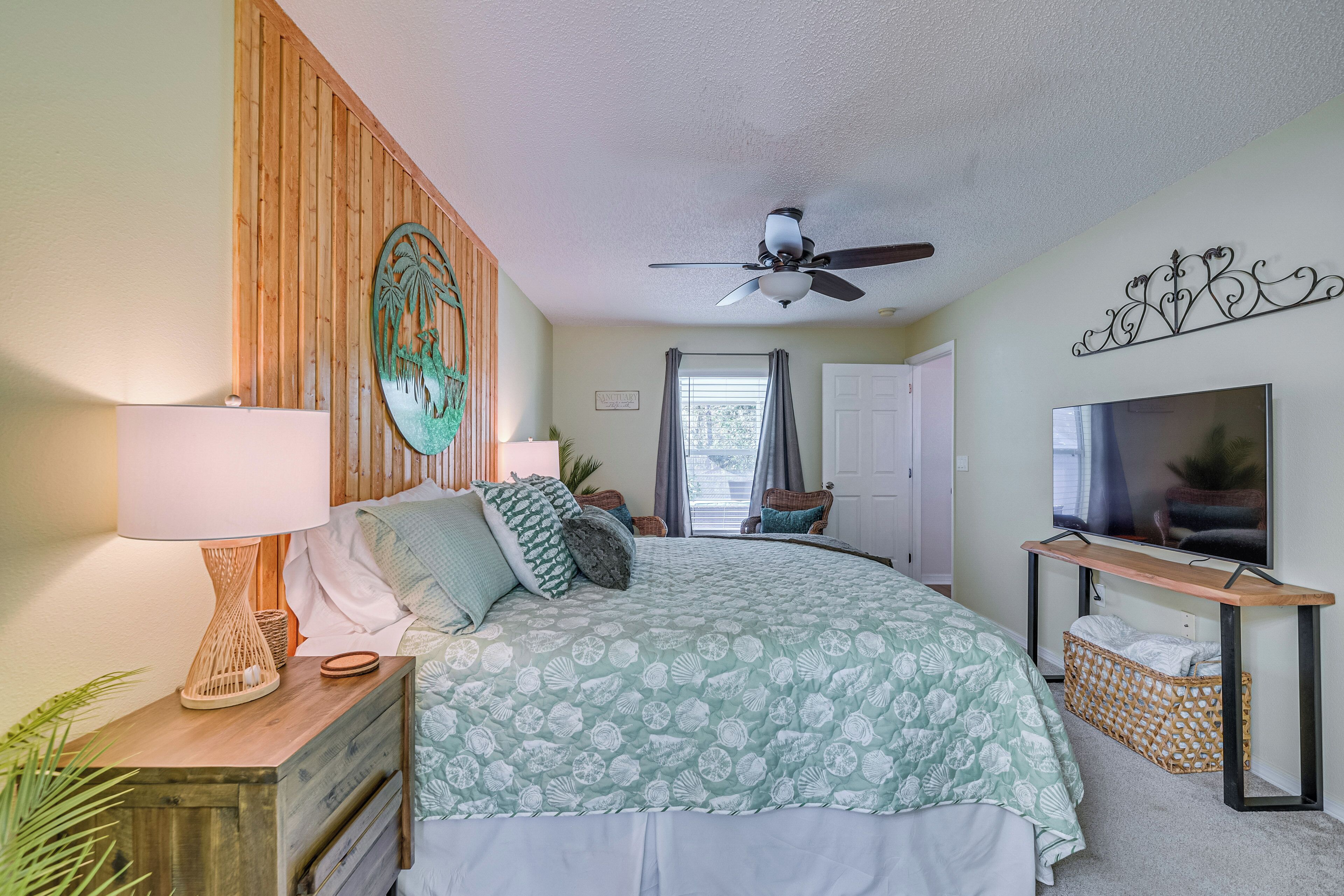A bedroom with a bed, a ceiling fan, a TV, and a wooden headboard.