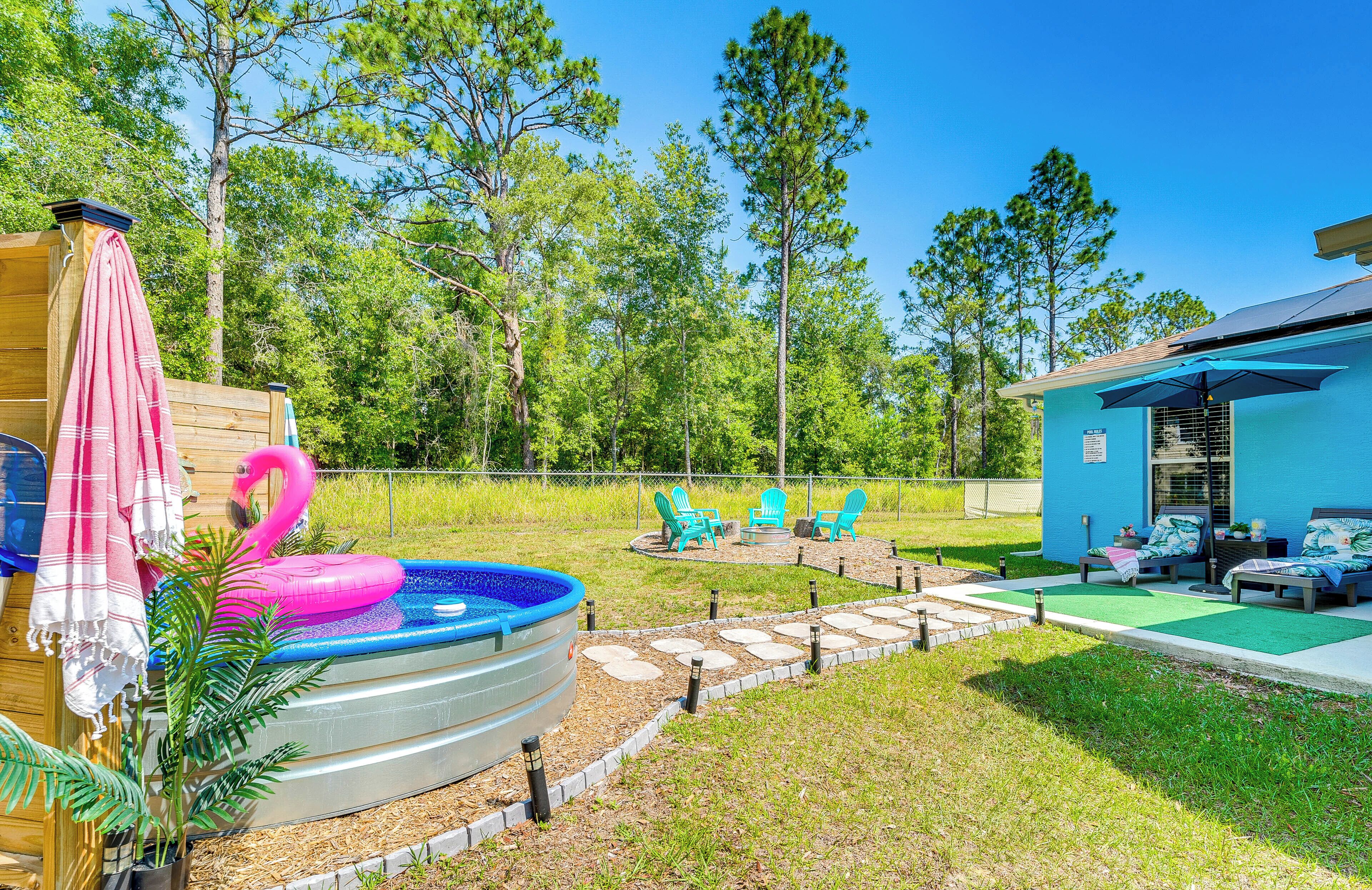 A backyard with a swimming pool, inflatable flamingo, and outdoor seating area.
