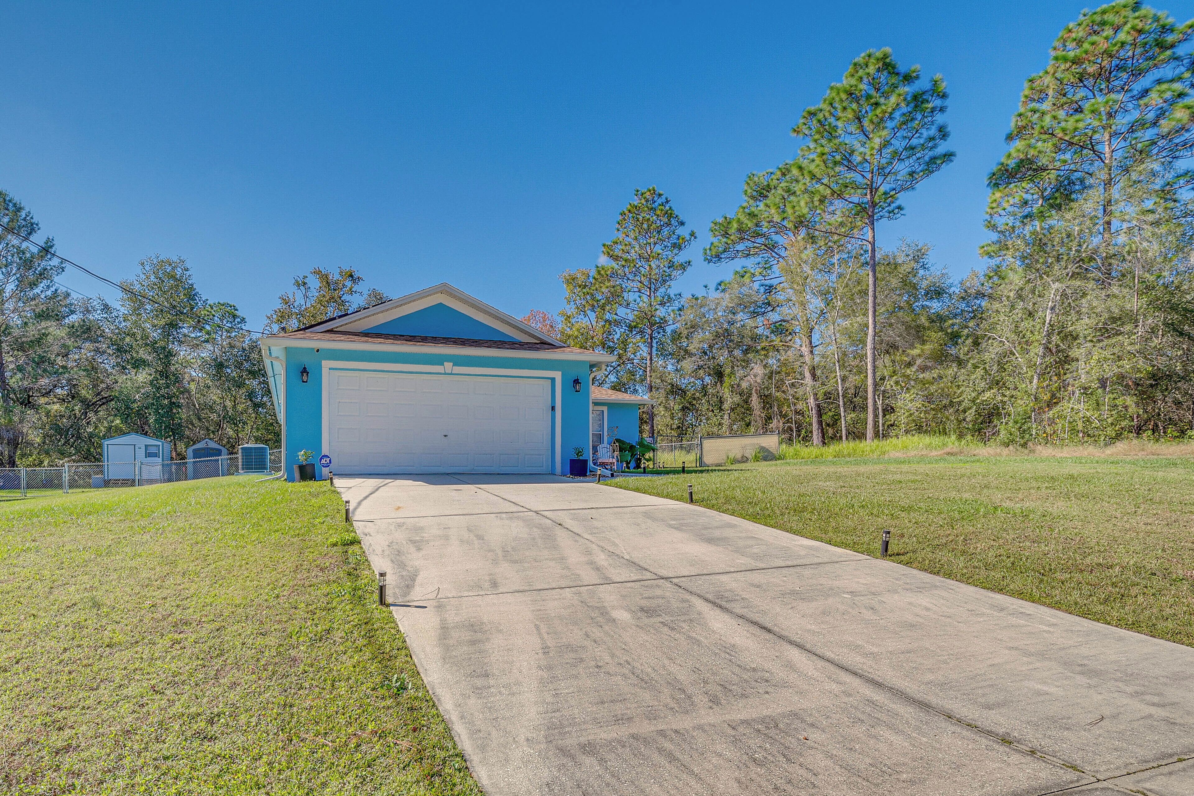 A garage with a concrete driveway leading to a blue building.