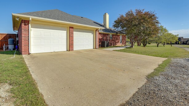 Une maison à deux étages avec un garage, une cheminée et une pelouse bien entretenue.