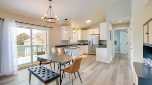 A modern kitchen with a dining area, large windows, and a view of the outdoors.
