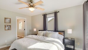 A bedroom with a bed, bedside lamps, a ceiling fan, and a nightstand.
