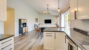 A modern kitchen with white cabinets, a granite countertop, and a built-in dishwasher.