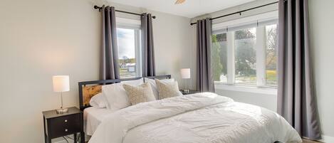A bedroom with a bed, nightstands, a ceiling fan, and a window with curtains.