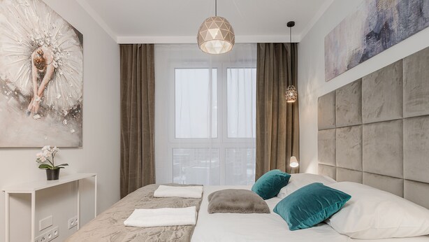 A modern bedroom with a large bed, a bedside table, a wall-mounted artwork, and a window with curtains. - Mokotów Domaniewska 47a (Warsaw)