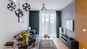 A modern living room with a dining area, a sofa, a coffee table, and a TV. - Mokotów Domaniewska 47a (Warsaw)