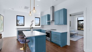A modern kitchen with blue cabinets, a white island, and stainless steel appliances. - Splendor in the Hills, Wimberley, Putting Green, Views, Hot tub! (Wimberley)