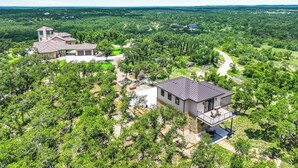 A large estate with multiple buildings, including a main house with a patio and a separate garage. - Splendor in the Hills, Wimberley, Putting Green, Views, Hot tub! (Wimberley)