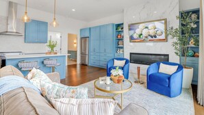 A modern living room with a sofa, armchairs, a coffee table, and a fireplace. - Splendor in the Hills, Wimberley, Putting Green, Views, Hot tub! (Wimberley)