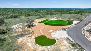 A golf course with a road curving alongside it. - Splendor in the Hills, Wimberley, Putting Green, Views, Hot tub! (Wimberley)