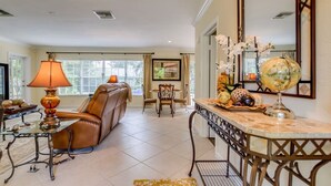 Un salon spacieux avec un canapé en cuir, une table basse en verre et un coin repas comprenant une table et des chaises.