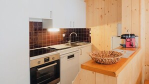Une cuisine de taille réduite, équipée d’une cuisinière, d’un four, d’un évier et de meubles de rangement en bois.