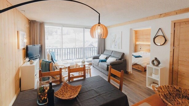 Une pièce confortable avec une table à manger, des chaises, un canapé, une télévision, un lit et un balcon.