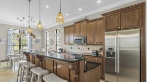 A kitchen with wooden cabinets, stainless steel appliances, and pendant lighting. - Golf Cart ~ Pet Friendly ~ Golf Course View (Miramar Beach)