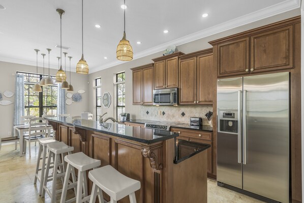 A kitchen with wooden cabinets, stainless steel appliances, and pendant lighting.