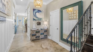 A hallway with a wooden console table, a large abstract painting, and a staircase with a green door. - Golf Cart ~ Pet Friendly ~ Golf Course View (Miramar Beach)