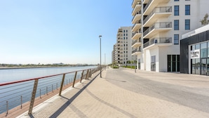 Een waterkantpromenade met moderne gebouwen, een heldere lucht en een rustige rivier.