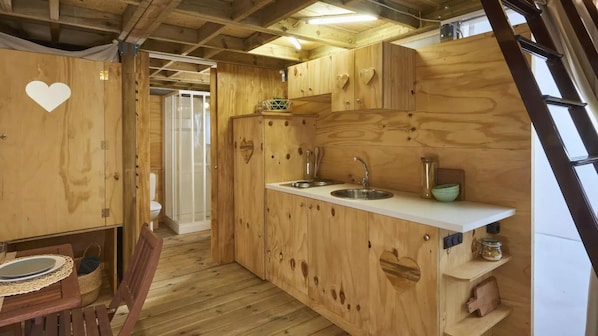 Una cocina de madera compacta con un lavamanos, armarios y un comedor con mesa y sillas.