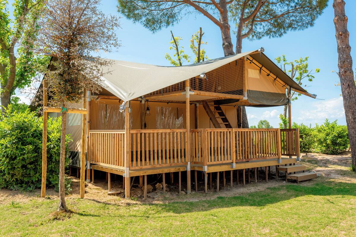 Una cabaña de madera con terraza cubierta y una escalera que conduce a un nivel superior.