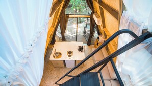 Ein kompakter, moderner Raum mit kleinem Tisch, Spüle, einer Treppe und Blick ins Freie.