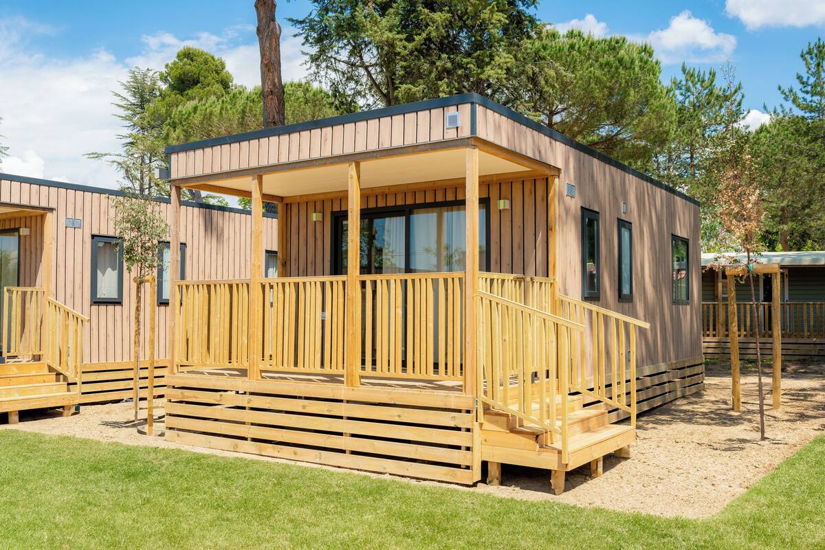 Una cabaña de madera con balcón, ventanas amplias y una puerta.
