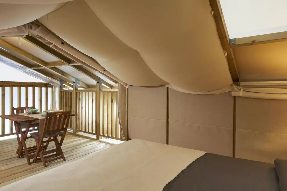 Un dormitorio con una cama de madera, una mesita con sillas y una lámpara.