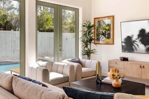 A living room with a pool, beige sofas, a coffee table, and a bookshelf.