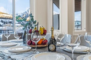 Tavola imbandita con piatti, bicchieri, una bottiglia di champagne e un vassoio di frutta.