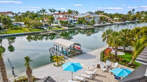 A waterfront property with a pool, lounge chairs, and a dock. - Waterfront w/Putting Green, Heated Pool, Dock -Manatee Cove (Lido Key)