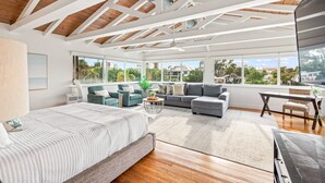 A spacious living room with a large bed, a grey sofa, and a dining area with a table and chairs. - Waterfront w/Putting Green, Heated Pool, Dock -Manatee Cove (Lido Key)
