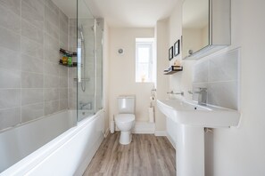 Ein modernes Badezimmer mit einer Duschkabine, einer weißen Toilette und einem weißen Waschbecken.