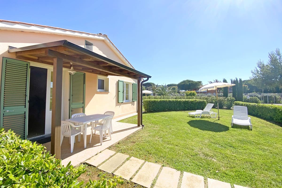 A house with a patio, outdoor seating, and a well-maintained lawn.
