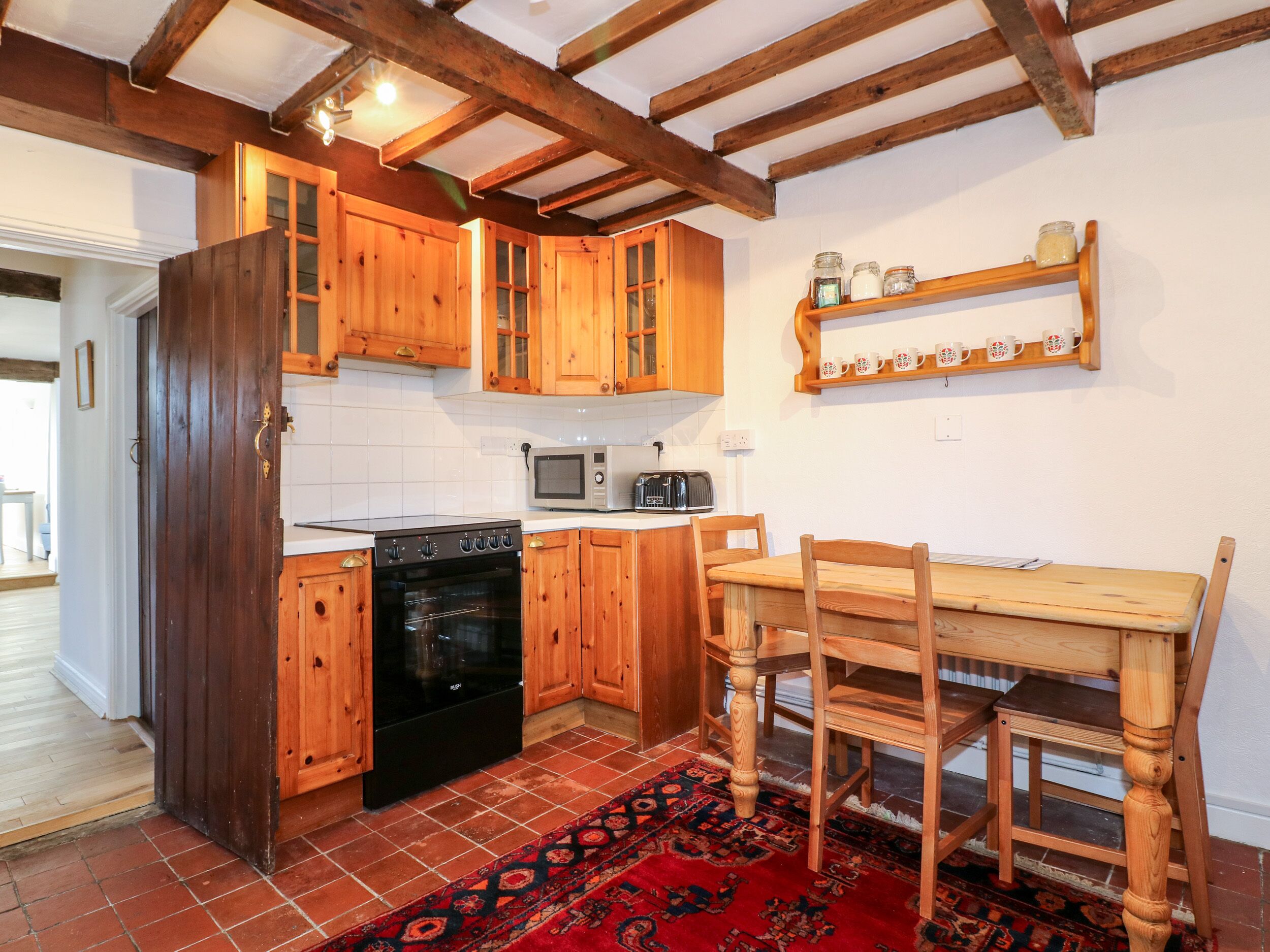 A kitchen with wooden cabinets, a microwave, an oven, and a dining table with chairs.