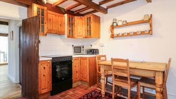A kitchen with wooden cabinets, a microwave, an oven, and a dining table with chairs.