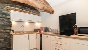 Una cocina moderna con armarios blancos, una pared de acento de piedra y un microondas negro grande.