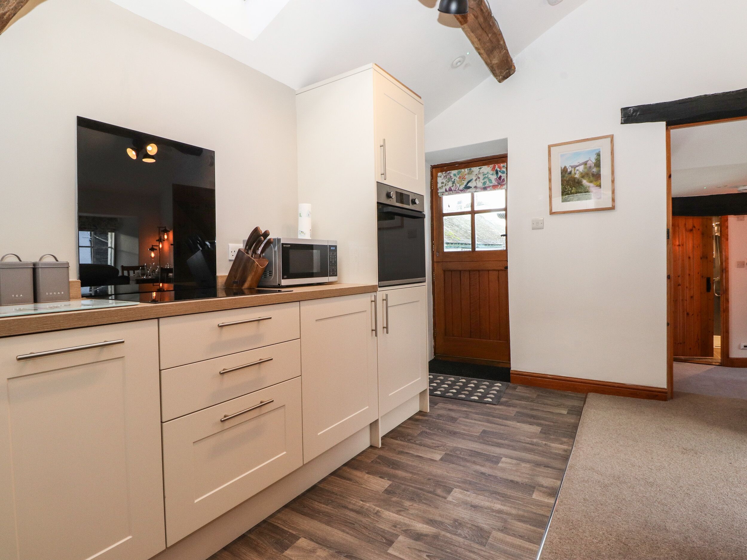 A modern kitchen with wooden cabinets, a microwave, and a sink.