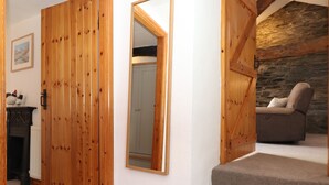 Una puerta de madera, un espejo, una escalera y una pared de piedra.