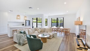 A modern living room with a sectional sofa, a round coffee table, and a dining area with a wooden table and chairs.