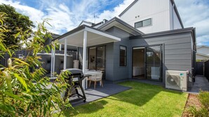 A modern house with a covered patio, a barbecue area, and a large window.