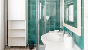 Un baño moderno con cabina de ducha de vidrio, un lavabo blanco y un espejo grande.