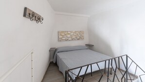 Un dormitorio con una cama, una obra de arte colgada en la pared, una mesita y una barandilla de escalera.